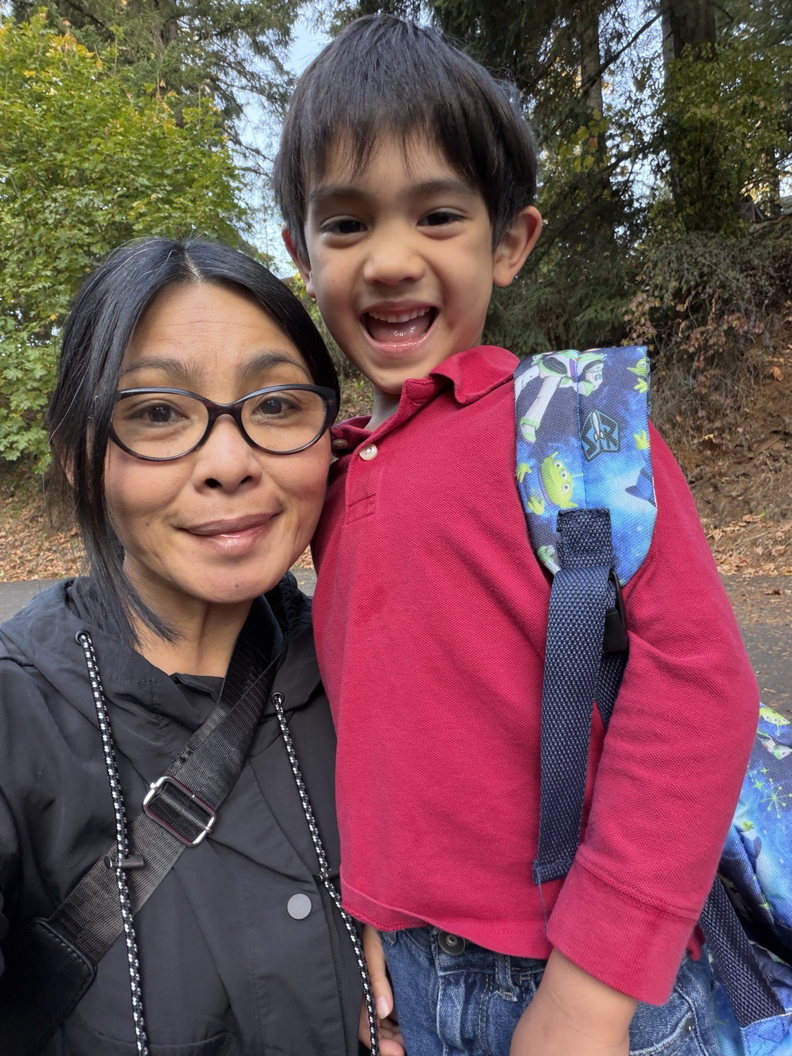 Madeline and her child smiling together outside among autumn trees